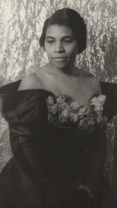 Black-and-white portrait of singer Marian Anderson in a dark off-shoulder dress with floral detail.